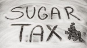 the words sugar tax written on a table in sugar