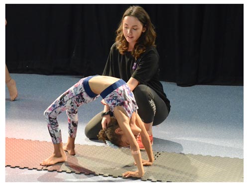 a coach helping a child perform a back bend