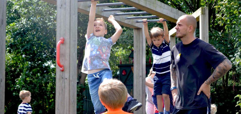 children playing on monkey bars while an adult keeps watch