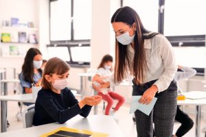 a teacher in a class helping a child sanitize their hands