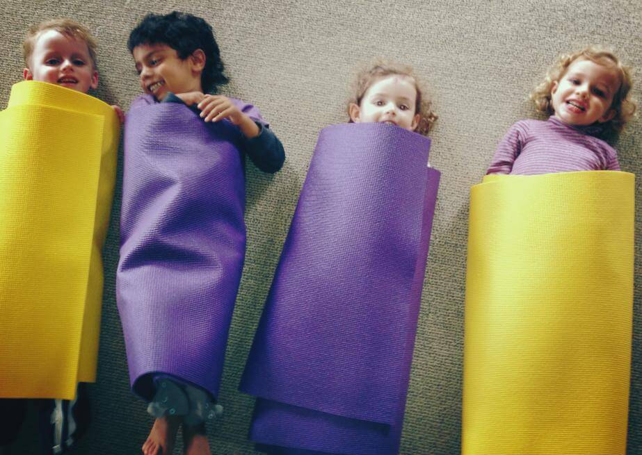 children wrapped up in yogmates smiling at the camera