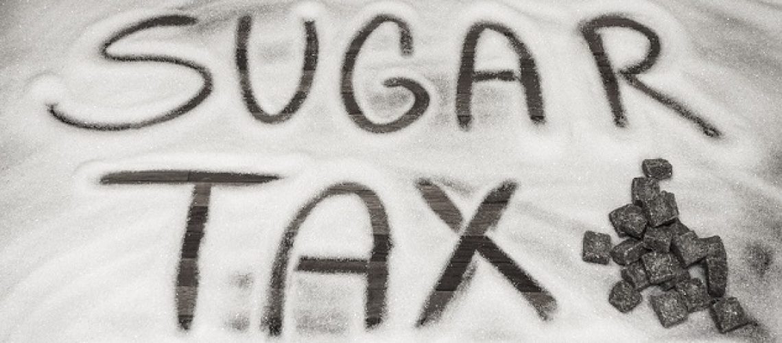 the words sugar tax written on a table in sugar